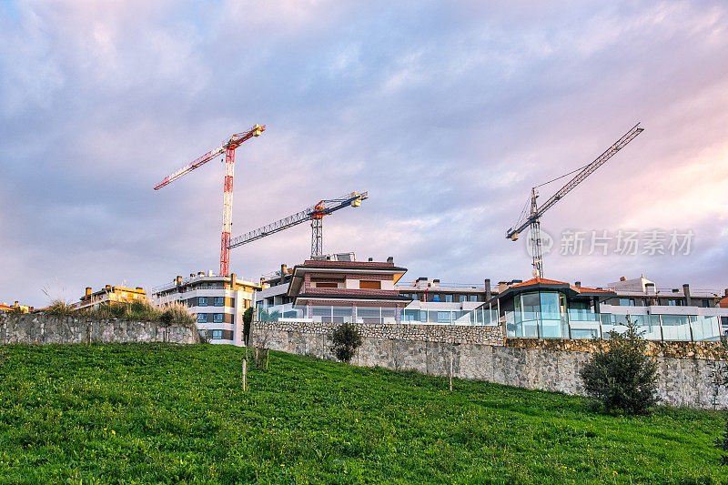 日落时分，建筑起重机在城市上空盘旋