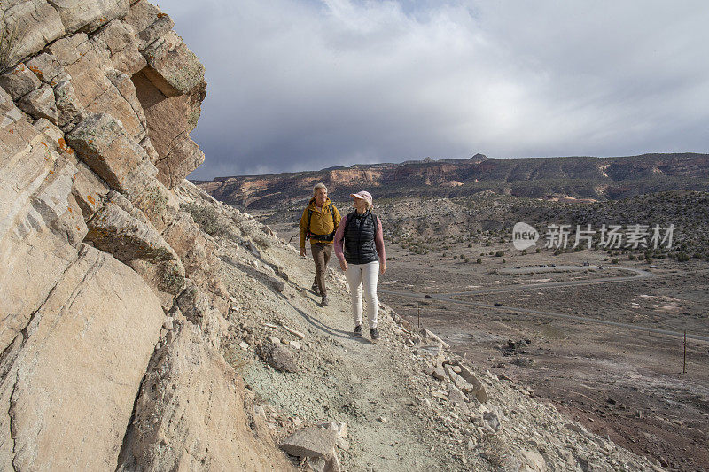 一对成熟的夫妇在早晨沿着阳光明媚的山脊徒步旅行