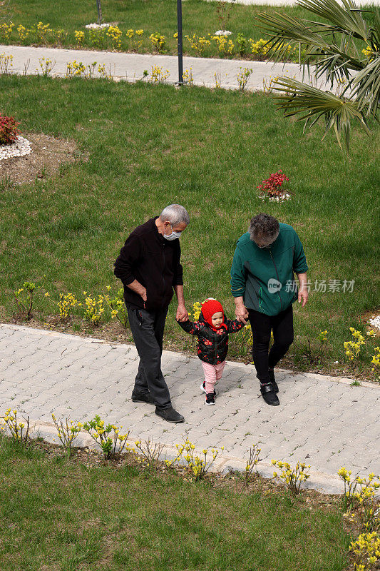 爷爷奶奶和小女孩戴着口罩走路