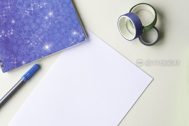 一张白纸，一张写有雪花的蓝色便条，一支毡头笔和一条亮闪闪的彩色装饰透明胶带。概念集中，冬天和明年的计划。