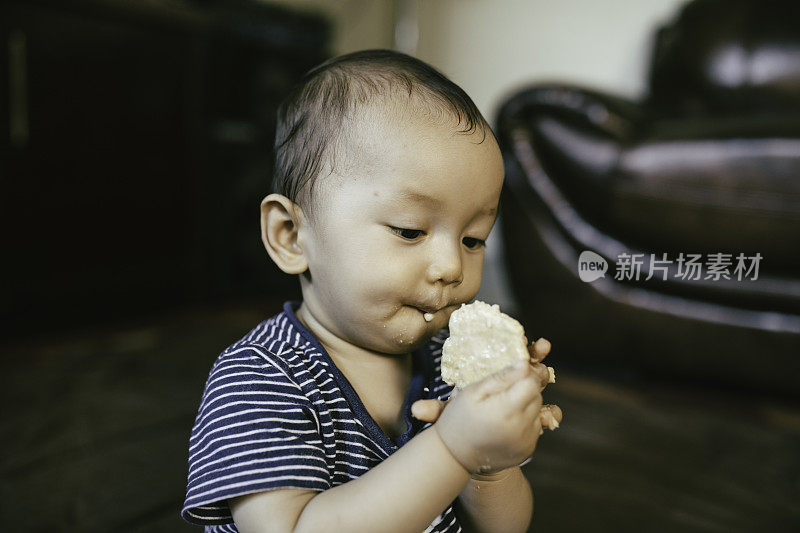 小男孩坐在地板上，脸上堆满了食物，面带微笑