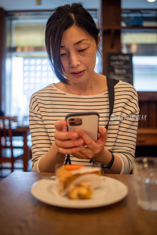 日本女人在咖啡馆拍甜点