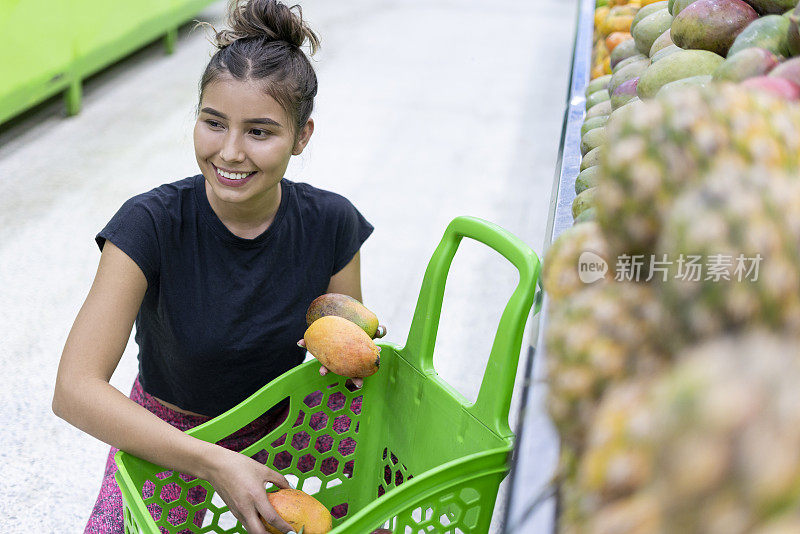 拉丁妇女杂货店顾客保持水果，她想买在她的购物车