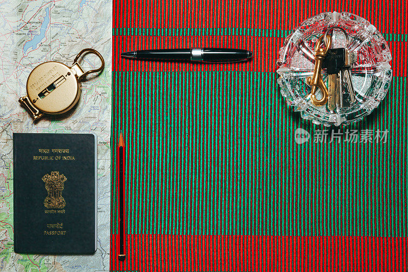 采购产品护照，地图，透镜罗盘，铅笔，钢笔和钥匙-准备在一个外国长时间的驾驶。在红色和绿色的编织织物上展示平整的空间，暗示圣诞节的来临。