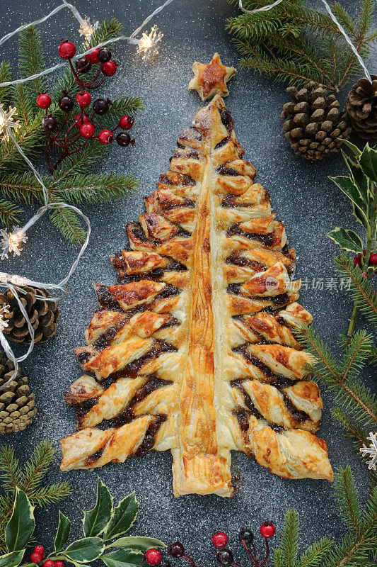 圣诞树形状的节日糕点甜点形象，酥脆的糕点充满了甜的肉馅(混合切碎的干果，蒸馏酒，香料)，洒上糖粉，高高在上
