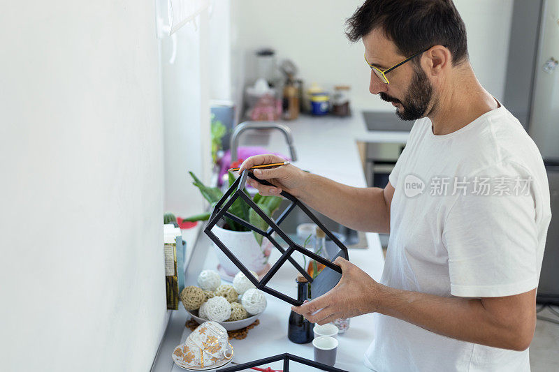 一个成熟的男人在厨房里架起了壁架