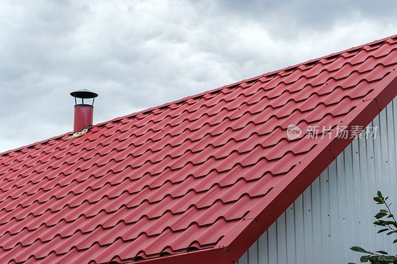 红色金属瓦做成的屋顶，在多云的天空下有一个烟囱。