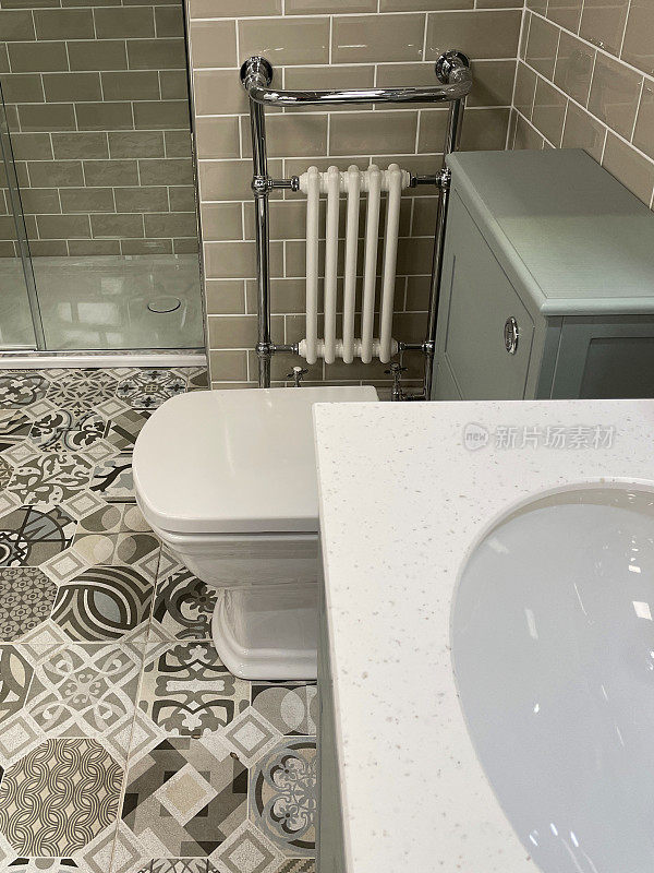 近景的现代浴室与白色，方形卫生间水箱隐藏在灰色的梳妆台，铬毛巾栏杆散热器挂在墙上的光滑瓷砖，棕色瓷砖，独立淋浴间，现代双水槽