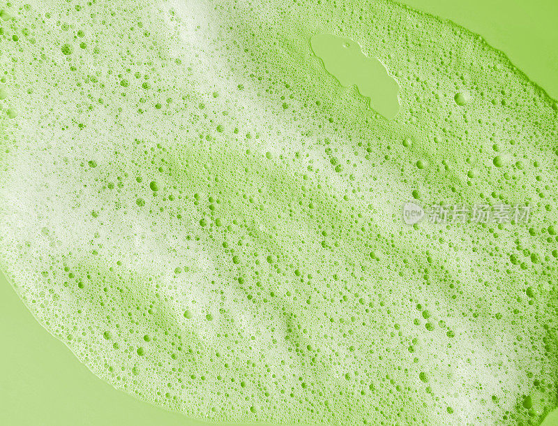 洁面摩丝样品。白色清洁剂泡沫泡沫在绿色的背景。香皂、沐浴露、洗发水泡沫纹理特写。