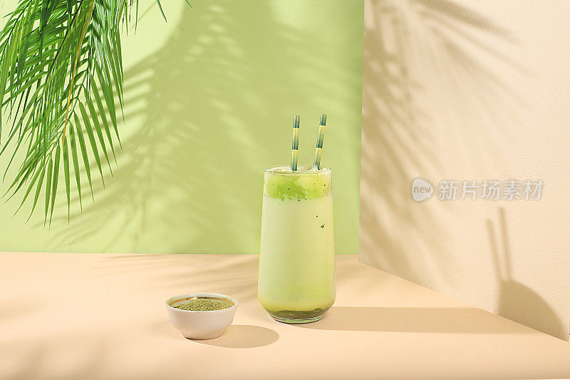 绿茶抹茶拿铁在玻璃与竹管在现代浅色背景与棕榈叶。传统的印度饮料富含抗氧化剂，