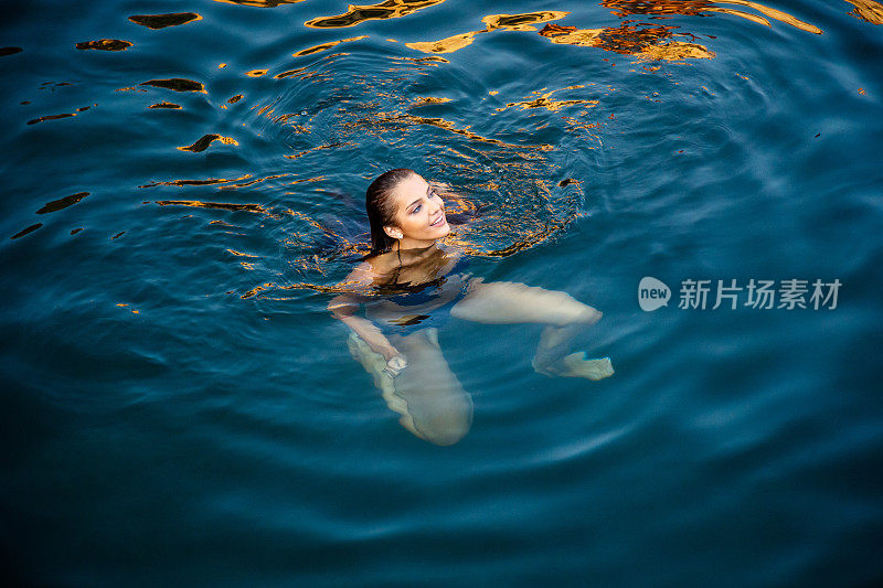 穿着比基尼的年轻女子快乐地漂浮在海水上