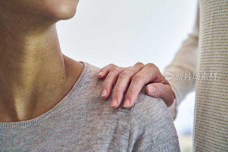 女人们把手放在肩膀上看着对方的特写