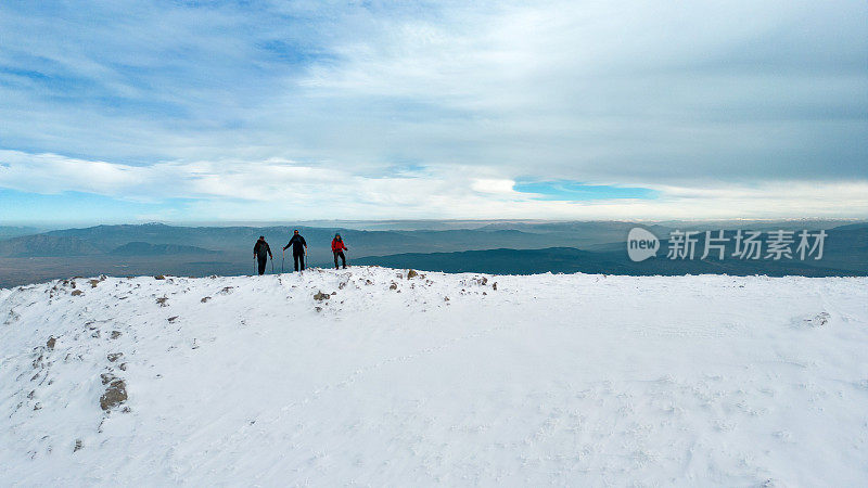 冬季，在雪山峰顶的山脊上，成功的登山队正对着相机排成一排