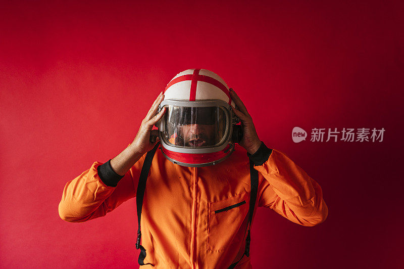 戴着头盔，穿着红色背景的橙色太空服的宇航员