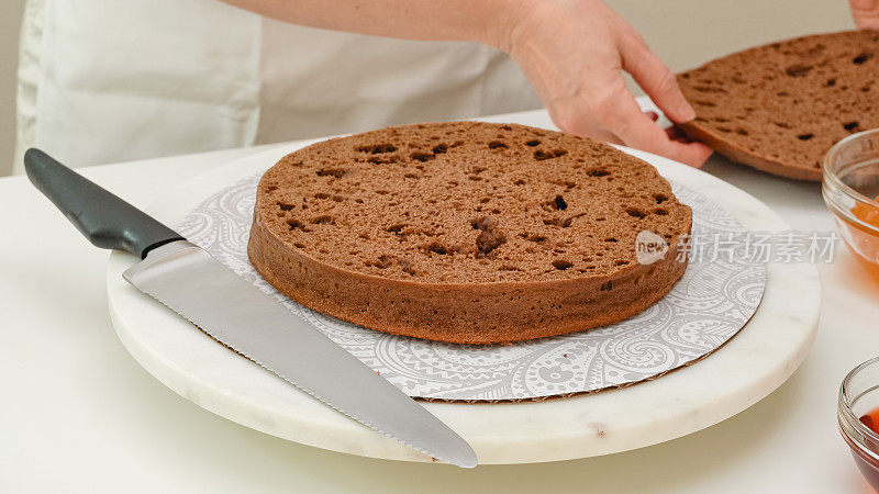 巧克力蛋糕的一步一步食谱。一名妇女用刀将刚烤好的蛋糕切成一层。