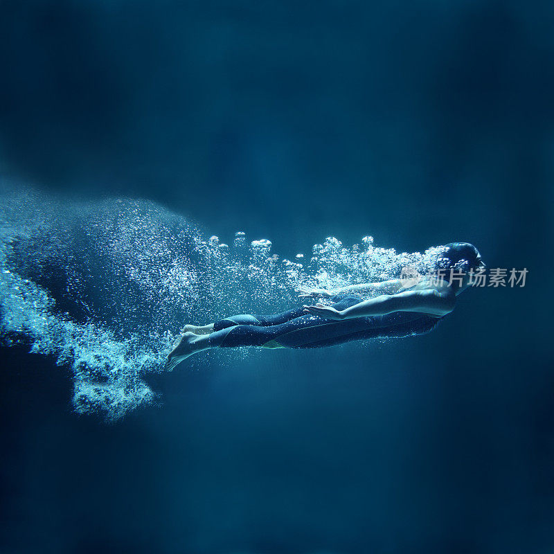 女性游泳者在水下流动的蓝色背景