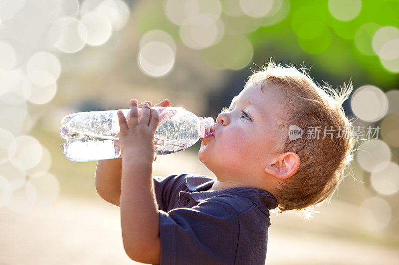 小男孩在外面，用水瓶喝水
