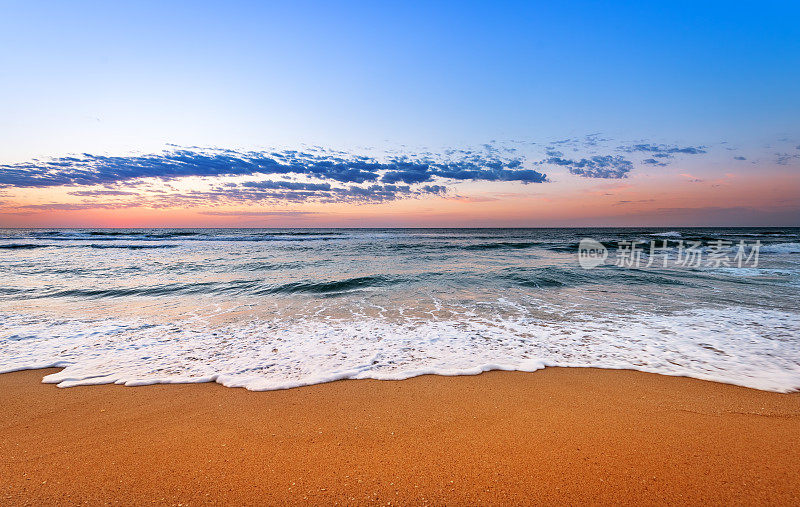 色彩斑斓的海滩日出与深蓝色的天空。