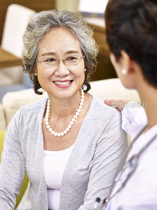 一位年长的亚洲女性正在和一位医务工作者交谈