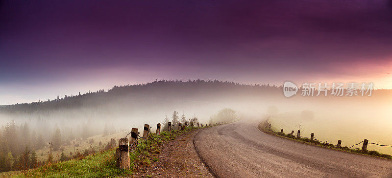 道路在山脉全景。美丽的春天晨雾在蜿蜒的山间