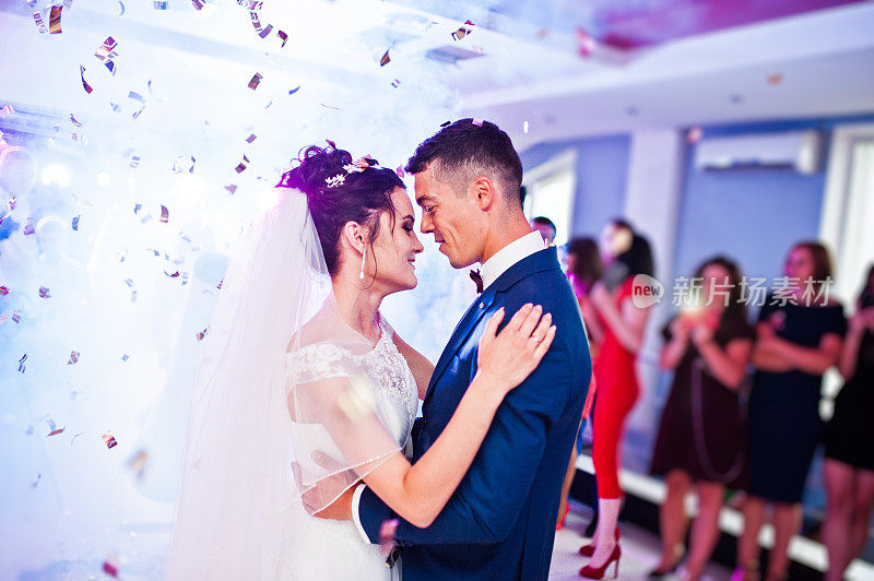 这是新人在婚礼上以五彩纸屑和彩灯为背景的感人的第一支舞。
