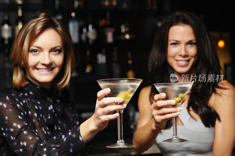 两个年轻女人在酒吧里敬酒喝马丁尼