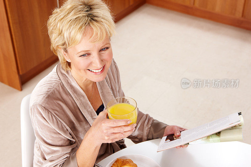 快乐成熟女人在家吃早餐的肖像