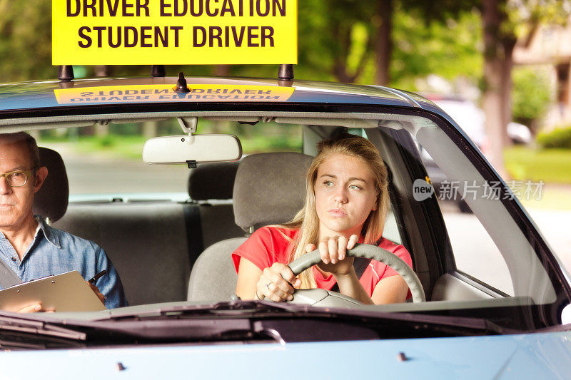 警惕、紧张的女学生司机正在参加驾驶教育课考试