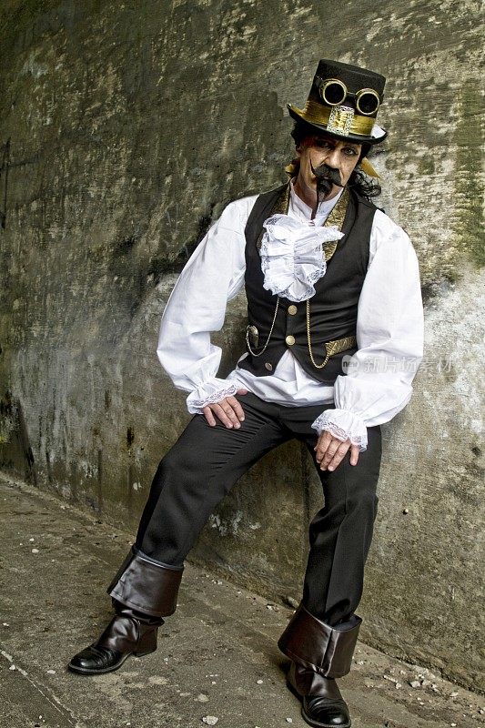 男子穿着蒸汽朋克，维多利亚时代的服装，深色的墙壁背景