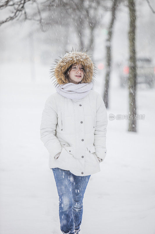 雪下穿着白色夹克的漂亮少女