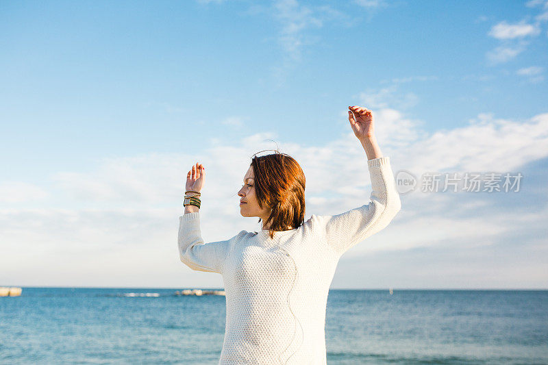 年轻女子在海滩上戴着耳机听音乐