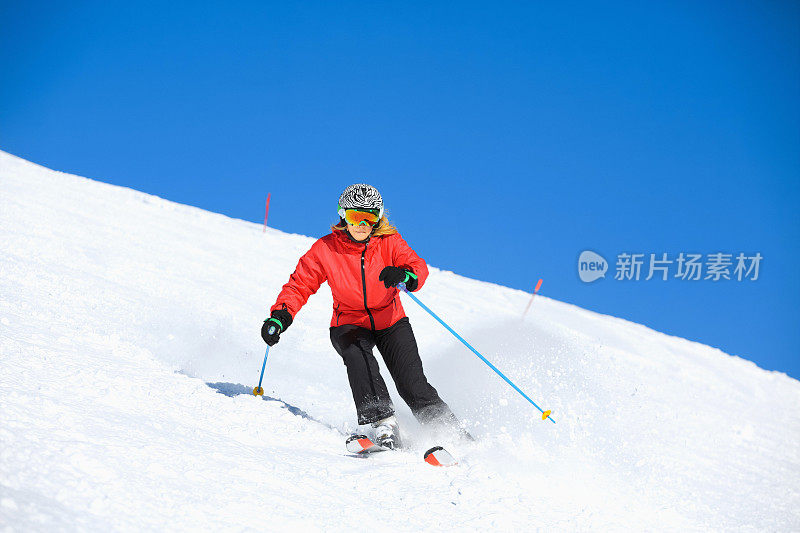 在阳光明媚的滑雪胜地滑雪的中年妇女滑雪