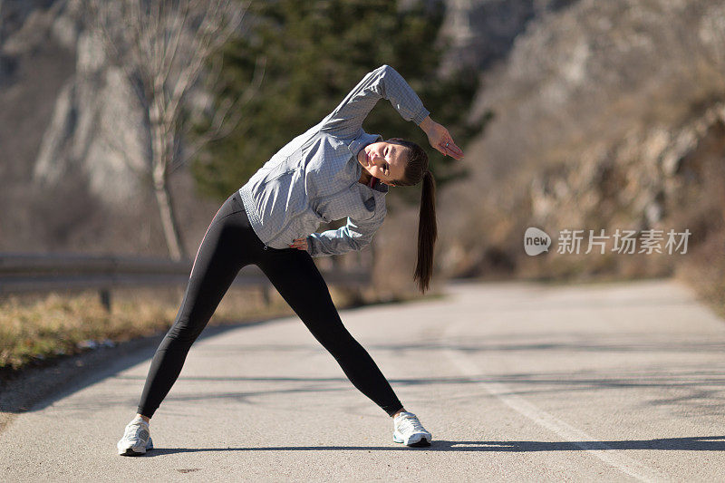 年轻的健身妇女在运动前伸展肌肉