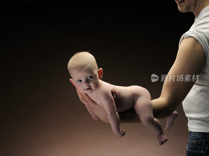 赤裸的男婴躺在男人的手臂上，XXXL图片