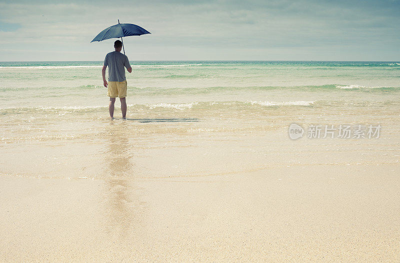 拿着雨伞的男人走进了大海