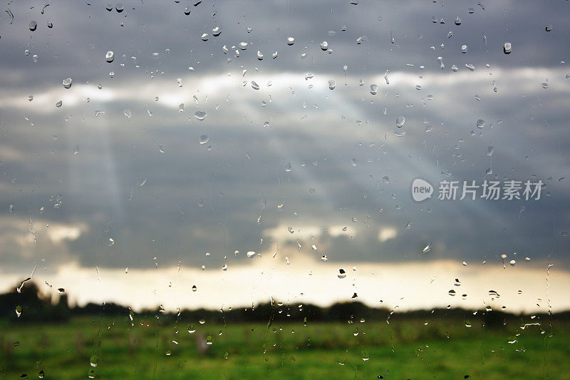 透过雨滴覆盖的窗户看到的阳光和云彩