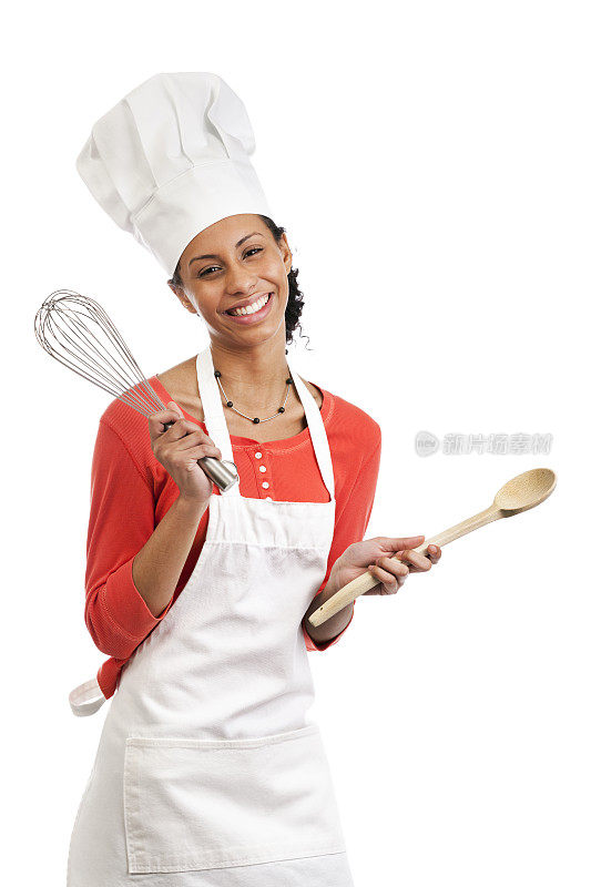 年轻女厨师穿着围裙，拿着白色的厨房用具
