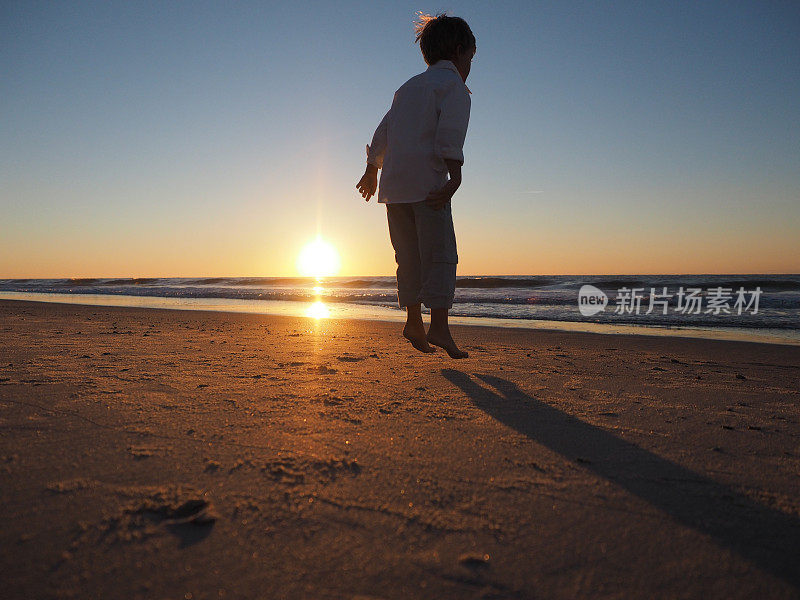 男孩在海滩上空中跳跃