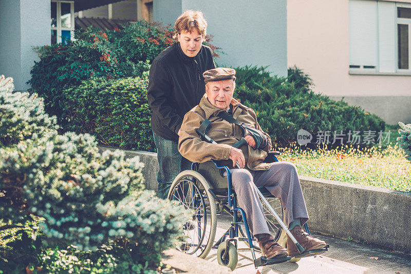 坐在轮椅上的老人和他的孙子在欧洲城市