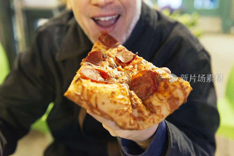午餐吃辣香肠披萨的男人