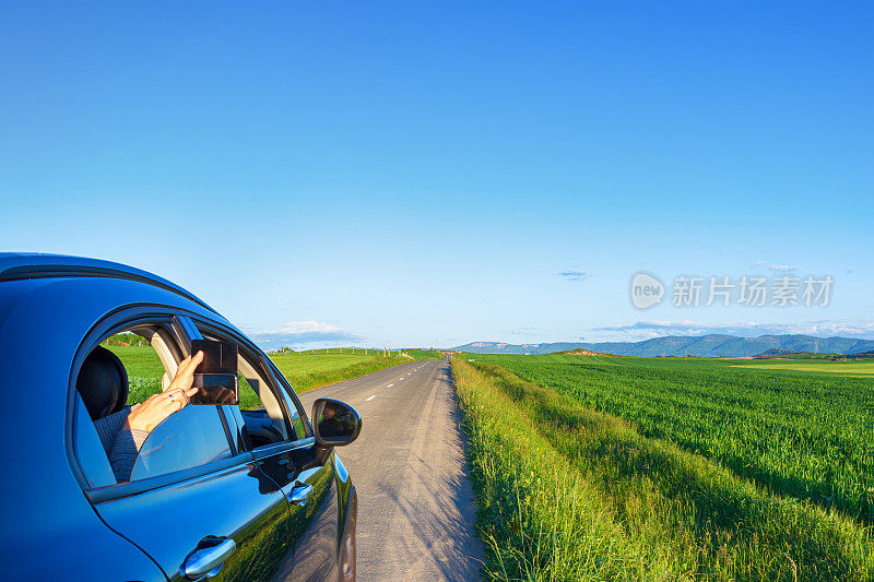 一个女人在车里拍风景照。