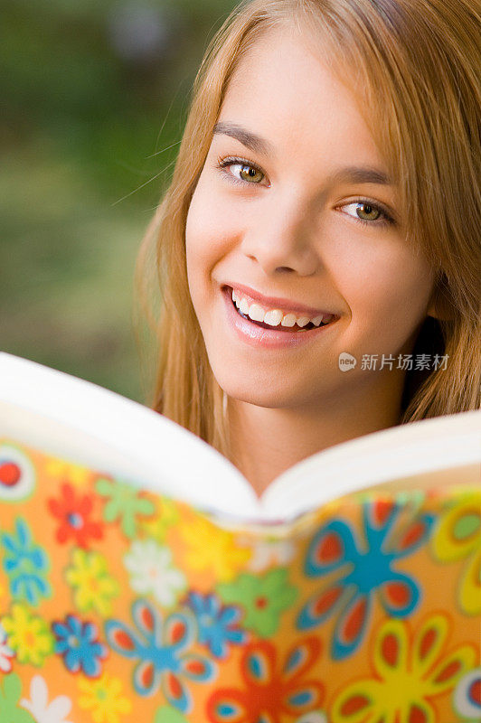 一名十几岁的女学生微笑着从课本上抬起头