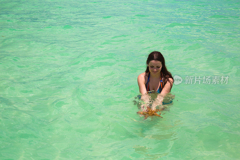 湿漉漉的年轻女子超长头发在绿松石海水手里拿着大海星