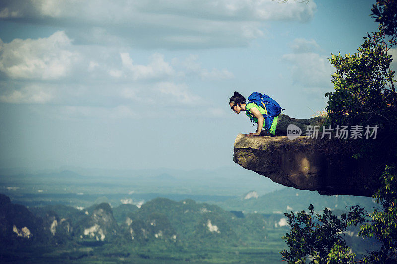 勇敢的女徒步旅行者躺在悬崖上向下看