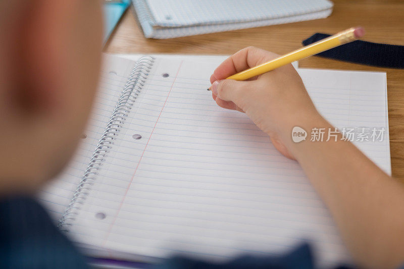 一个面目全非的十几岁的男孩准备在一张白纸上写字