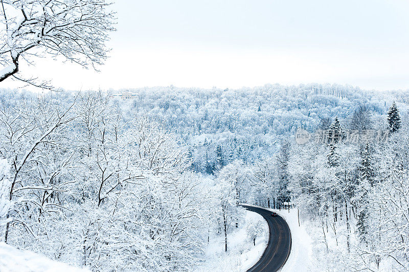景色与冬天的道路和雪山上冻结的林地