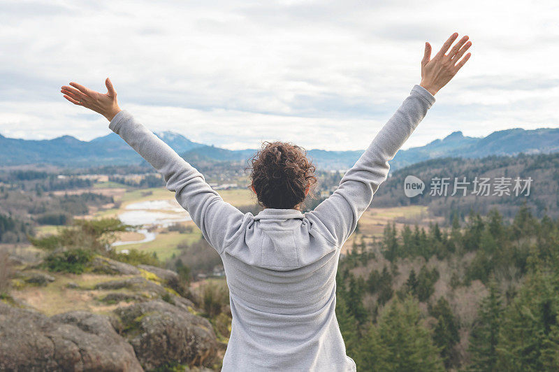 年轻的民族女性徒步旅行者举起她的手在热情