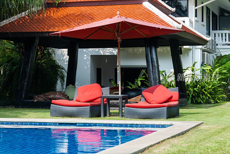 红色沙滩椅和雨伞旁边的游泳池