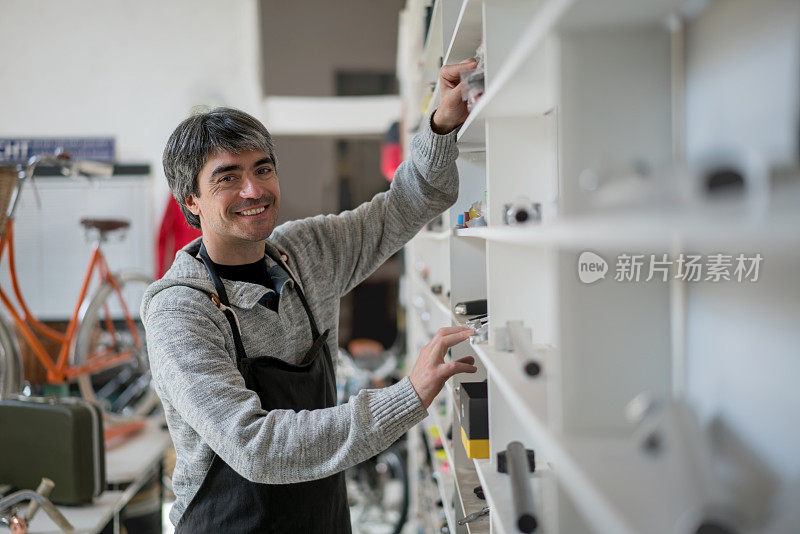 一个成年人在他的自行车修理店看着相机微笑的肖像