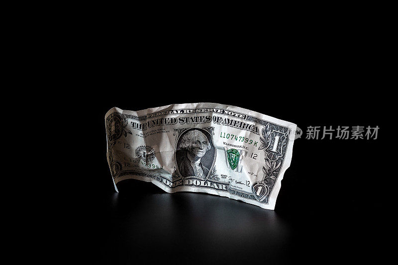 在黑暗的背景下，一美元被孤立地揉皱了